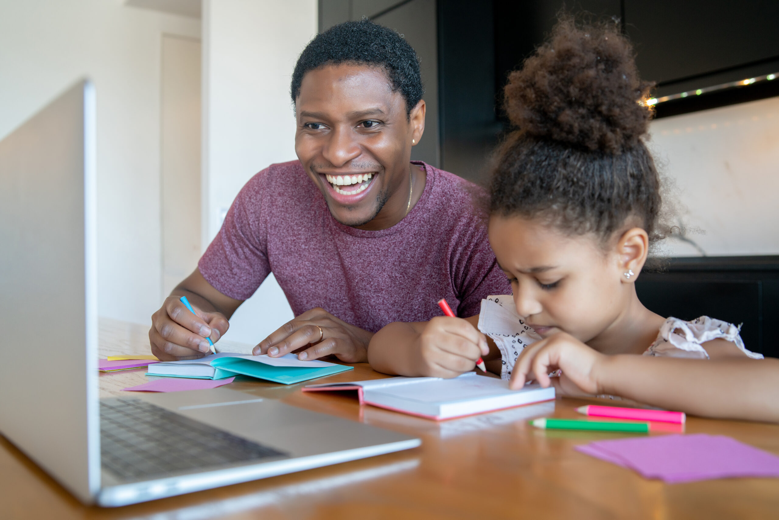 Father helping and supporting his daughter with online school while staying at home. New normal lifestyle concept.
