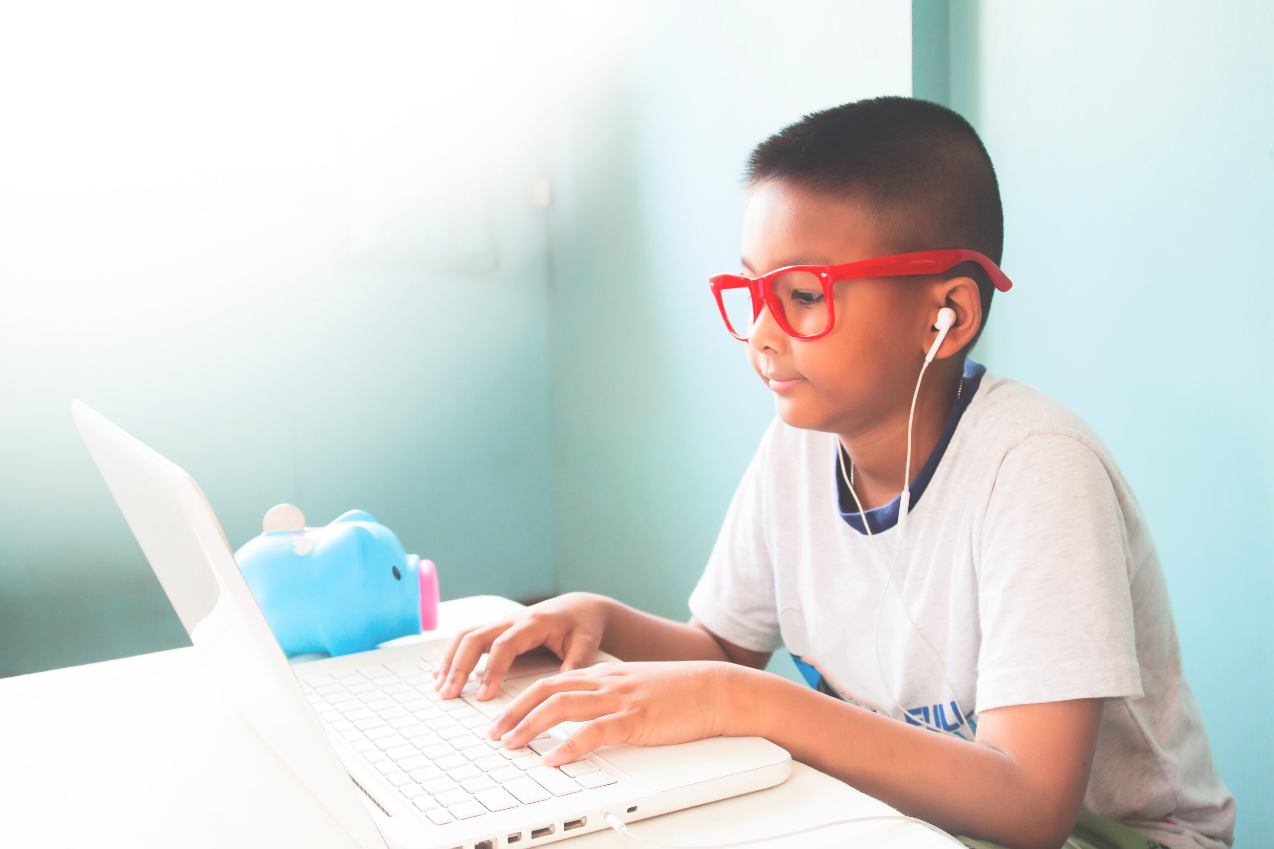 Little boy child wearing red glasses listening and using laptop computer